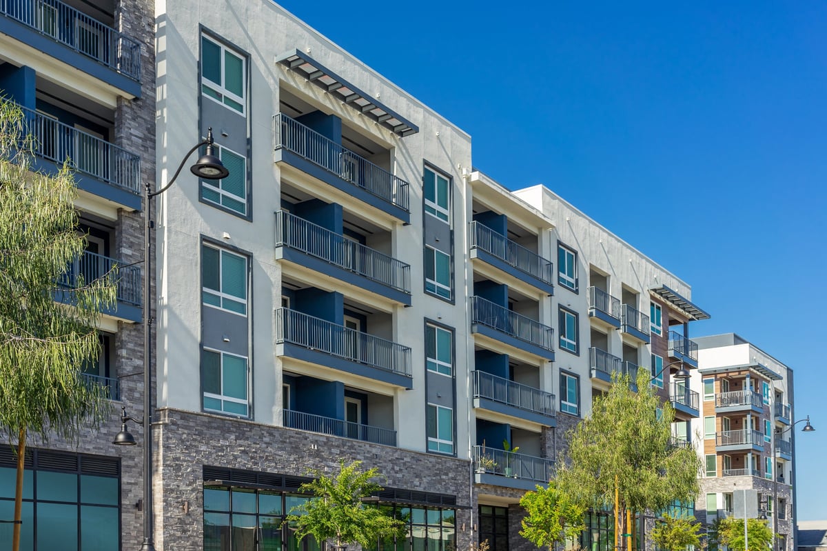 A modern apartment building with balconies and blue sky, symbolizing quality affordable housing